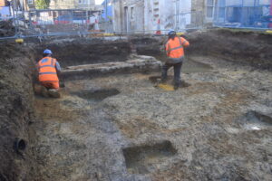 Several archaeological ditches and archaeologists at a construction site