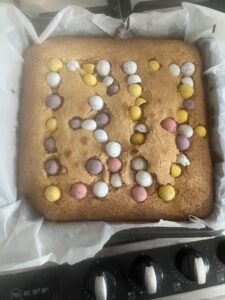 A picture of a cake in baking paper with 1317 written on it in mini eggs.