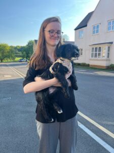 Regular Giving Officer, Lydia Smith, stood in the street holding her puppy, Lemon, who is looking off into the distance