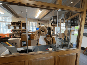 A Teddy Bear mascot answering a phone in the lodge at St Edmund Hall